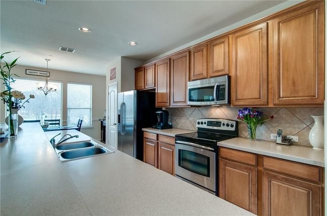 Kitchen featuring sink, a chandelier, appliances with stainless steel finishes, pendant lighting, and backsplash | Image 7