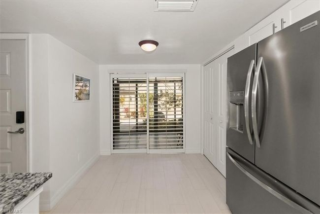 Kitchen with stainless steel fridge, white cabinets, and light stone countertops | Image 8