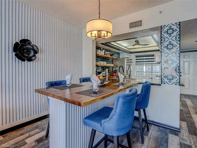 CUSTOM INTEGRATED DINING ISLAND W/ACACIA WOOD TOP AND FLUTED WOOD ACCENT BASE. ENTRANCE TO UNIT IS SHOWN AT REAR RIGHT. | Image 7