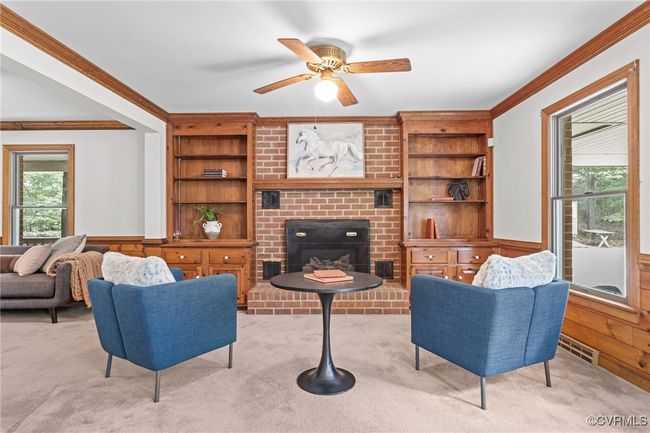 Living room with crown molding, built in shelves, light colored carpet, ceiling fan, and wainscoting | Image 5