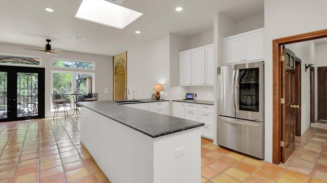 Kitchen featuring stainless refrigerator, a sink, white cabinets, a peninsula, and recessed lighting | Image 16