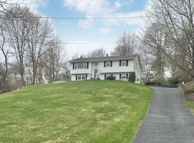 Raised ranch with aphalt driveway, a front yard, and a chimney | Image 24