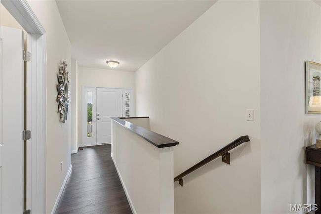 Hallway with an upstairs landing, dark wood-style flooring, and baseboards | Image 11