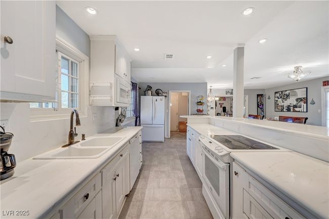 Kitchen with white appliances, a sink, white cabinetry, recessed lighting, and light countertops | Image 46