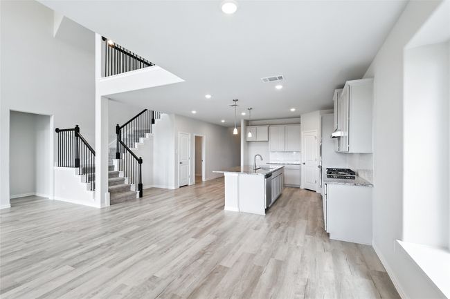 Kitchen with light wood finished floors, a kitchen island with sink, open floor plan, stainless steel gas cooktop, and recessed lighting | Image 9