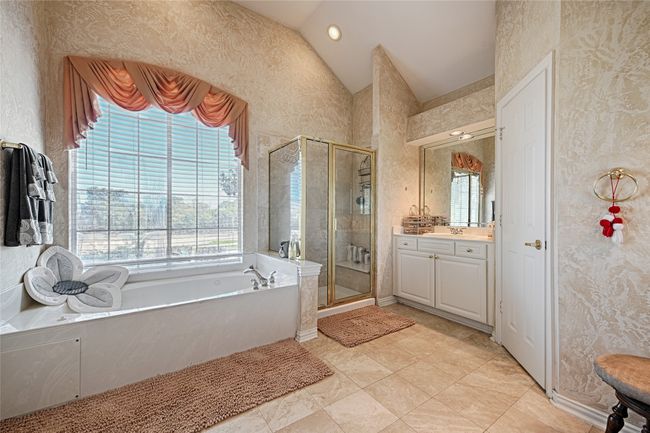 Bathroom featuring a garden tub, vanity, vaulted ceiling, a stall shower, and wallpapered walls | Image 34