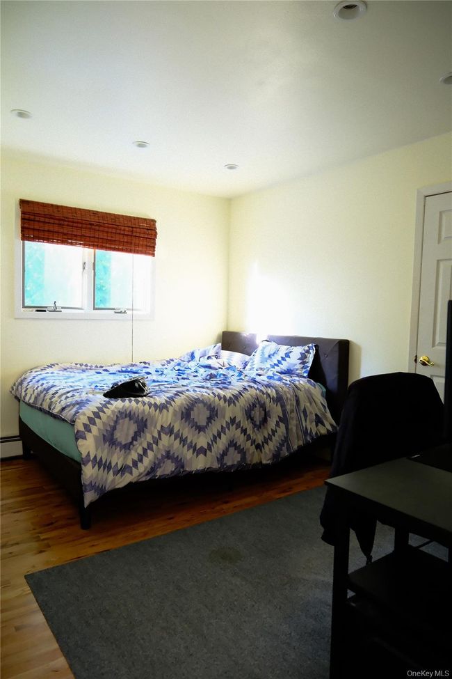 Bedroom with wood finished floors and a baseboard heating unit | Image 18