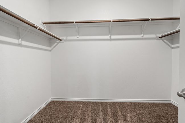 Walk in Primary closet featuring carpet and shelving with wood hanger rods | Image 21