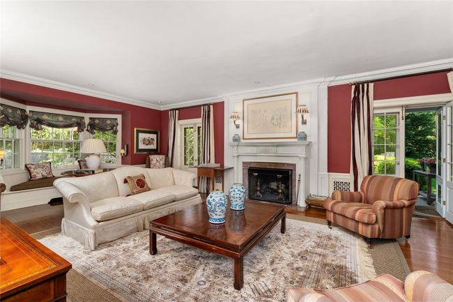 Living area with healthy amount of natural light, crown molding, wood finished floors, and a premium fireplace | Image 6