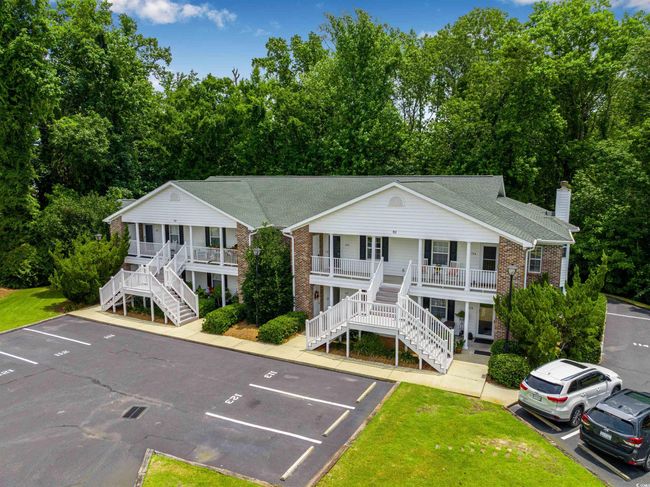 View of property featuring stairway, uncovered parking, and view of scattered trees | Image 31