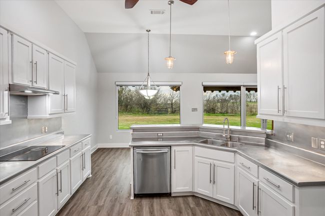Kitchen featuring white cabinets, stainless steel counters, lofted ceiling, and hanging light fixtures | Image 28