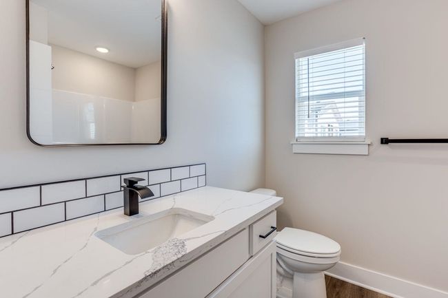 Bathroom with vanity, toilet, baseboards, wood finished floors, and decorative backsplash | Image 15