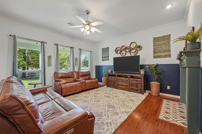 Living room with wood finished floors, ceiling fan, crown molding, and baseboards | Image 5