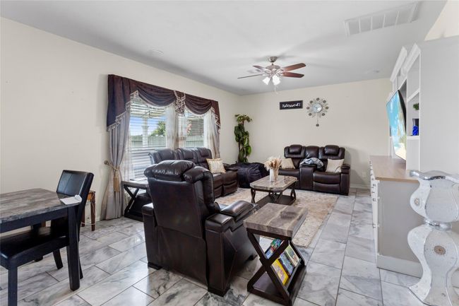 The living room features elegant tile flooring and abundant natural light from large windows | Image 10