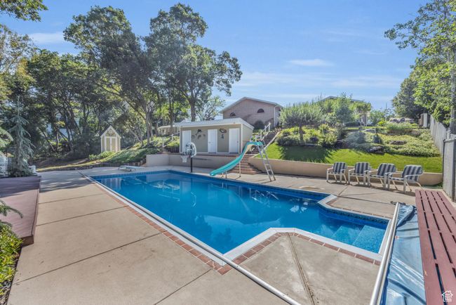Outdoor pool with a patio area and a water slide, diving board | Image 34