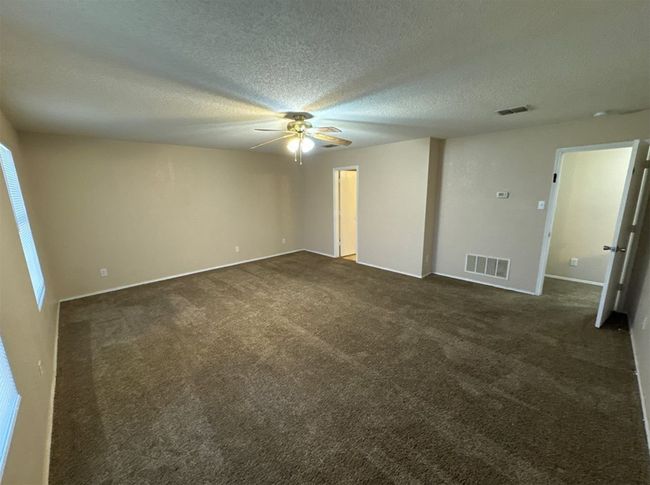 Unfurnished bedroom with ceiling fan, dark carpet, and a textured ceiling | Image 23