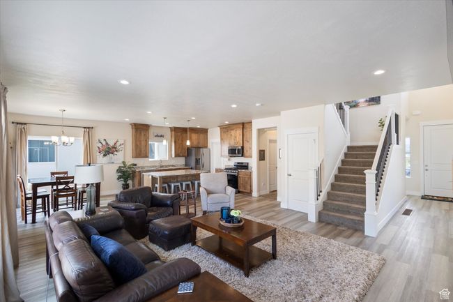 Living area featuring light wood-type flooring, stairway, a chandelier, and recessed lighting | Image 6