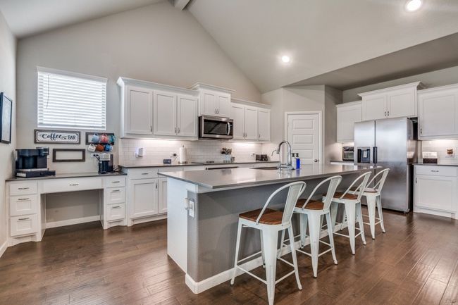 Kitchen with an island and a desk area. | Image 7