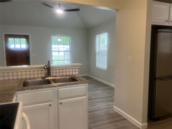 Kitchen featuring freestanding refrigerator, light wood finished floors, stove, white cabinetry, and healthy amount of natural light | Image 7
