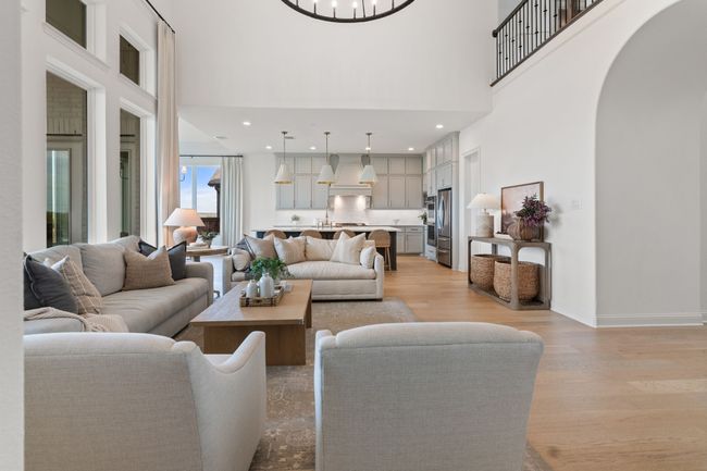 Living area with light wood-style flooring, arched walkways, recessed lighting, and a towering ceiling | Image 10