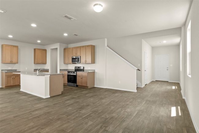 Kitchen with stainless steel appliances, recessed lighting, dark wood finished floors, a kitchen island with sink, and light stone countertops | Image 12