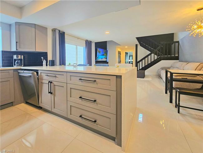 Kitchen with stainless steel dishwasher, open floor plan, light countertops, a peninsula, and gray cabinetry | Image 19