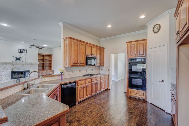 Kitchen featuring kitchen peninsula, tasteful backsplash, ornamental molding, black appliances, and sink | Image 24
