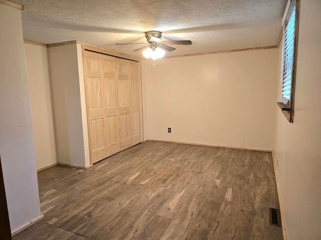 Unfurnished bedroom with ceiling fan, a textured ceiling, a closet, and hardwood / wood-style floors | Image 10