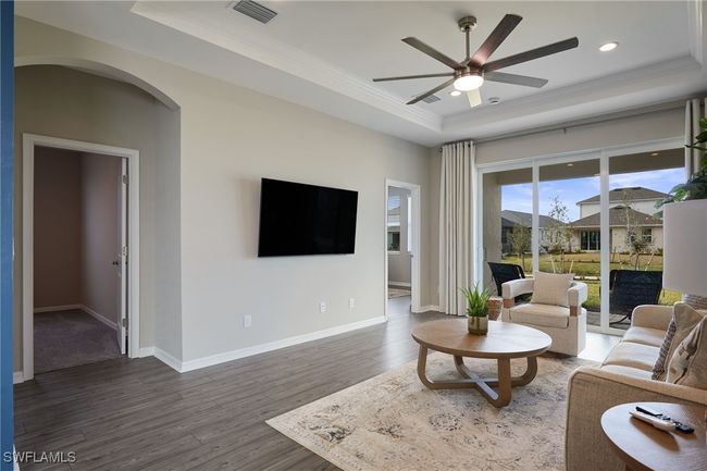 Living room featuring dark wood-style flooring, visible vents, baseboards, ornamental molding, and a tray ceiling | Image 5
