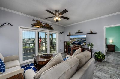 Living room with light hardwood / wood-style flooring, ornamental molding, a textured ceiling, and ceiling fan | Image 2