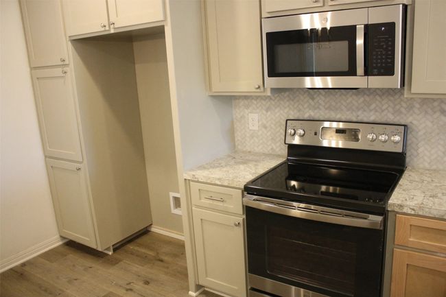 Kitchen featuring appliances with stainless steel finishes, light wood finished floors, backsplash, and light countertops | Image 6