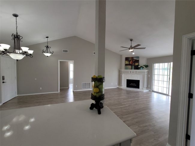 Unfurnished living room with ceiling fan, a brick fireplace, wood finished floors, lofted ceiling, and baseboards | Image 7