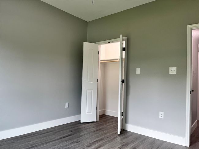 Unfurnished bedroom with dark wood-style flooring and a closet | Image 15