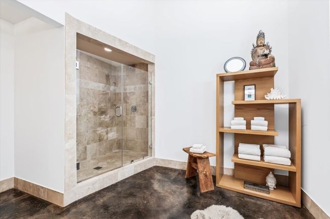 Primary bathroom with a large natural stone walk-shower and stained concrete flooring | Image 31