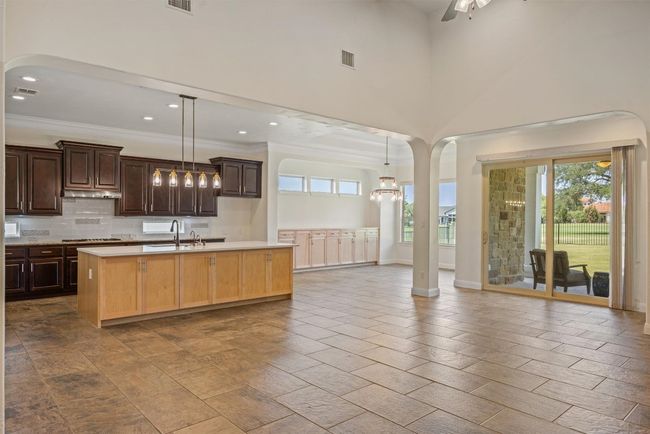 Kitchen featuring newer birch wood & quartzite counter and sink, decorative light fixtures, open floor plan, tasteful backsplash, windows and dark brown cabinets, open concept to the living and dining rooms | Image 16