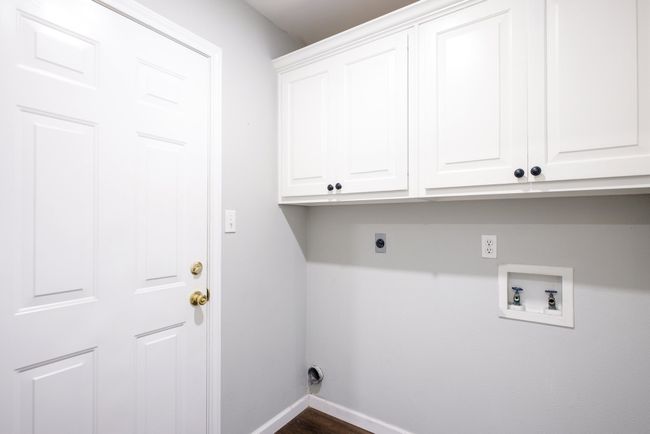Laundry room with electric dryer hookup, cabinet space, hookup for a washing machine, and dark wood finished floors | Image 16