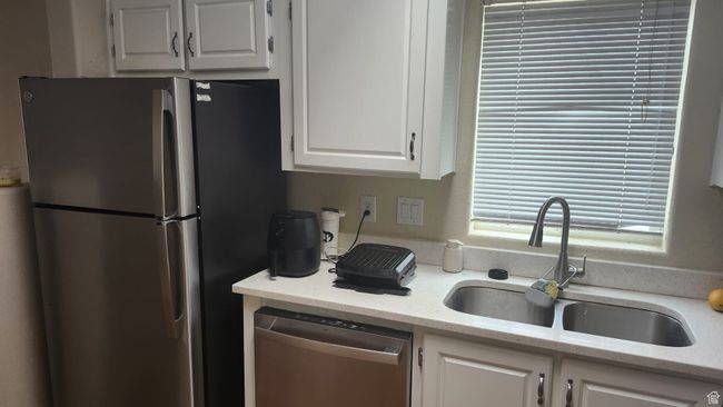 Kitchen featuring appliances with stainless steel finishes, a sink, white cabinetry, and light stone counters | Image 14