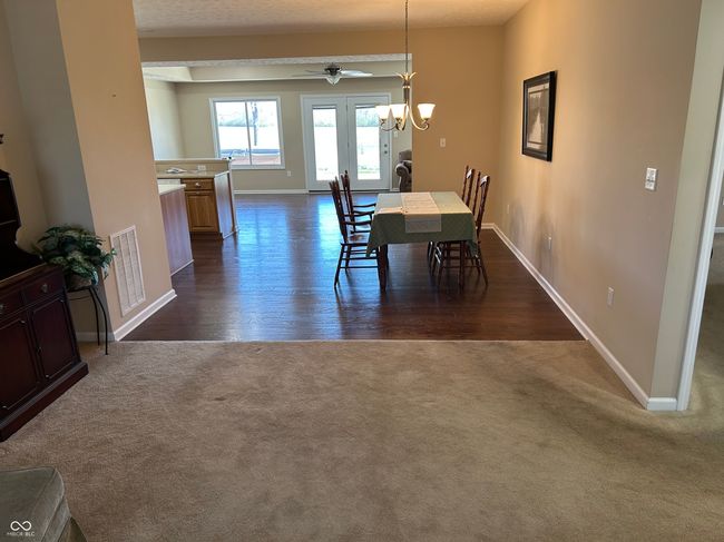 dining area with dark wood-style floors, baseboards, visible vents, ceiling fan with notable chandelier, and dark carpet | Image 4