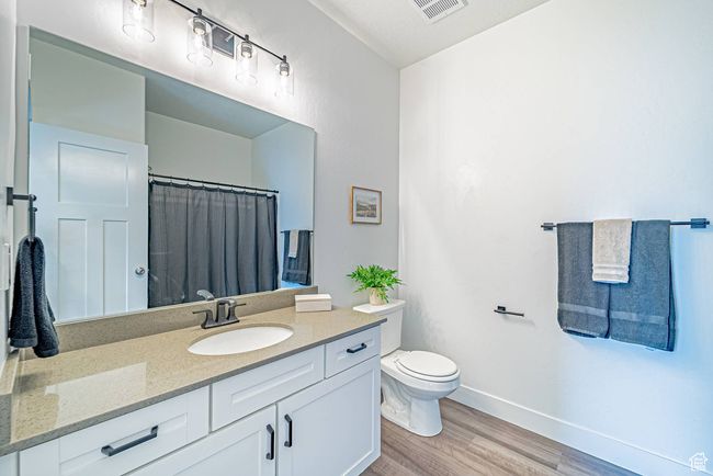Full bath featuring vanity, baseboards, toilet, visible vents, and wood finished floors | Image 14