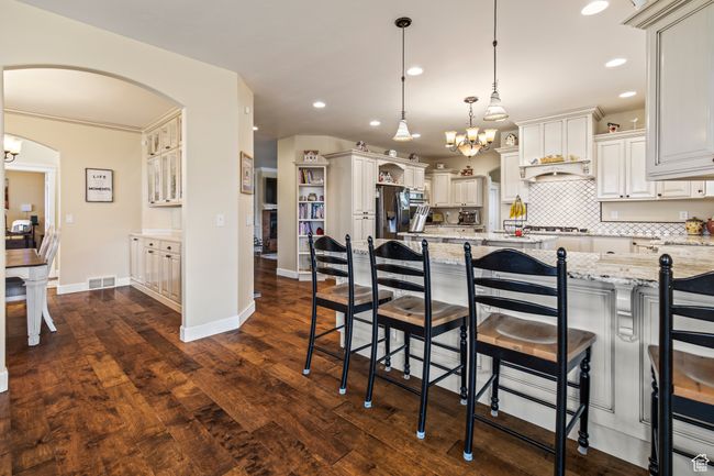 Kitchen with light stone countertops, pendant lighting, dark hardwood / wood-style flooring, and a kitchen breakfast bar | Image 33