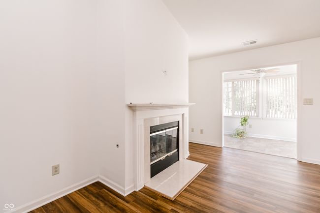 unfurnished living room with baseboards, a glass covered fireplace, dark wood-type flooring, and visible vents | Image 8