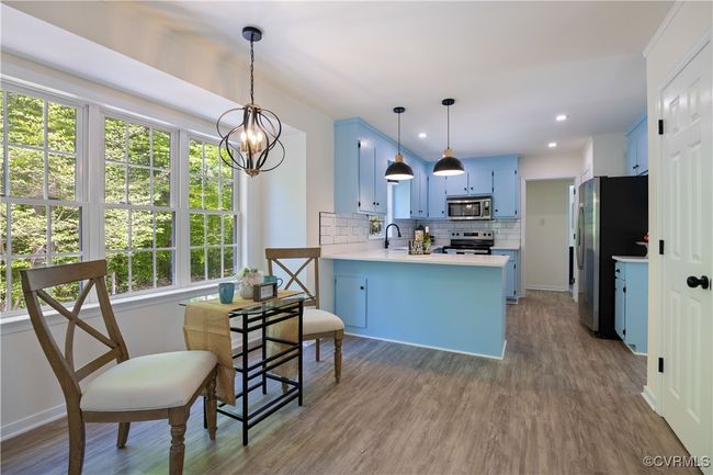 Kitchen with blue cabinets, a peninsula, decorative backsplash, light countertops, and appliances with stainless steel finishes | Image 16