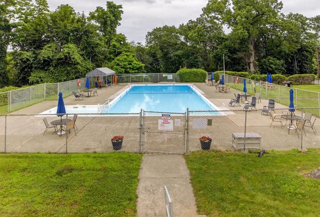 Community pool featuring a patio area and view of scattered trees | Image 39