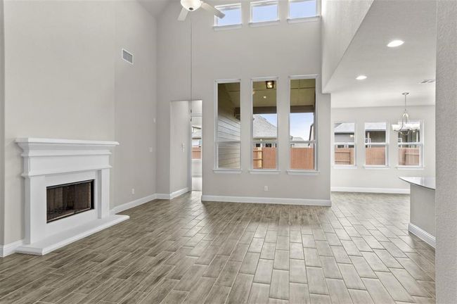 Unfurnished living room featuring healthy amount of natural light, a ceiling fan, wood finished floors, and a towering ceiling | Image 6