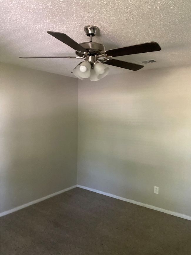 Empty room featuring a textured ceiling, visible vents, baseboards, and ceiling fan | Image 16