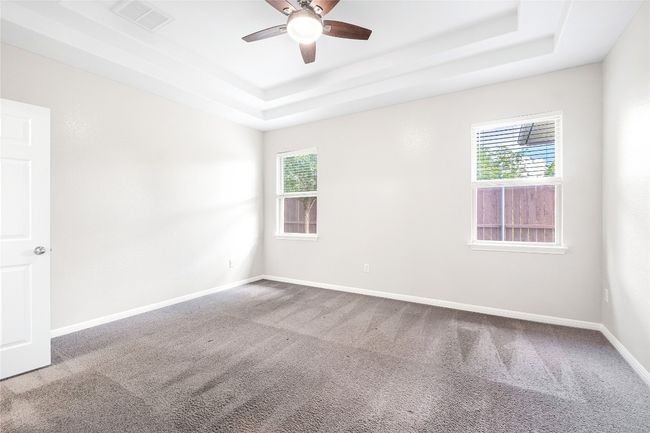 Carpeted spare room featuring a tray ceiling, healthy amount of natural light, and a ceiling fan | Image 34