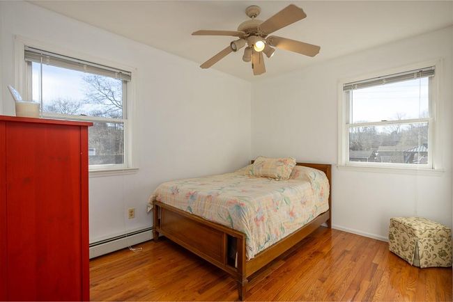 Bedroom with multiple windows, wood finished floors, ceiling fan, and baseboard | Image 14
