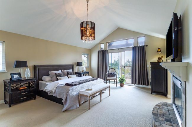 Bedroom featuring a fireplace, vaulted ceiling, baseboards, an inviting chandelier, and carpet | Image 17