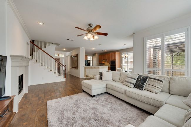 Living room with crown molding, wood-style flooring, baseboards, and stairway | Image 7
