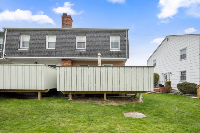 Rear view of house with a lawn, roof with shingles, a chimney, and mansard roof | Image 47